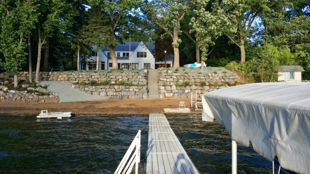 Two large tiers of fieldstone boulder walls retain the slope on this lakefront property.