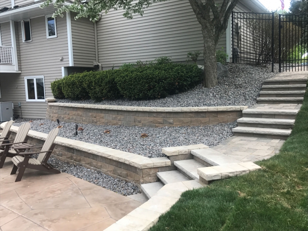 A two tiered block retaining wall and steps allow for a smooth transition to the backyard patio.