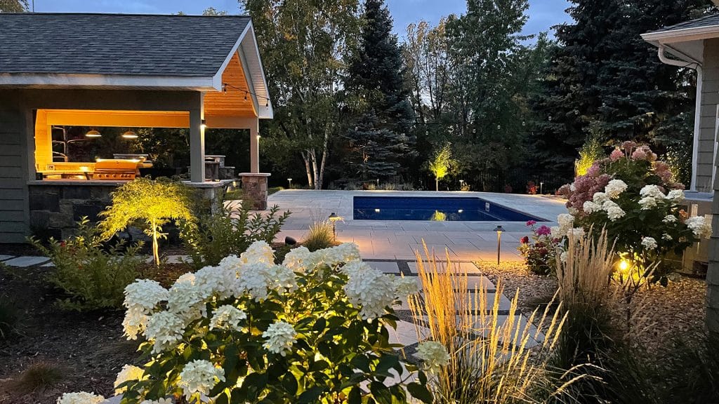 Outdoor lighting highlighting landscape features and pool area